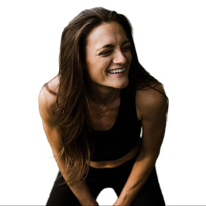 Woman in a black outfit sitting on grass with a blurred background