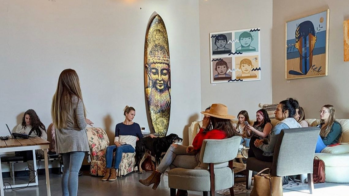 Group of people in a Color Up at House of VXN education class in a modern office setting with a surfboard and Buddha statue.