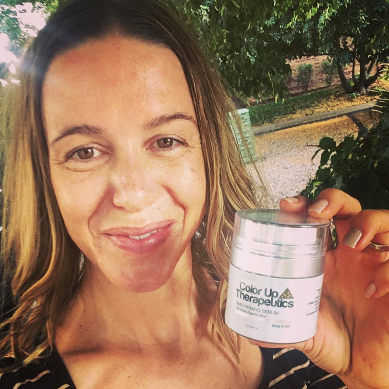Woman holding a jar of Color Up Therapeutics product outdoors