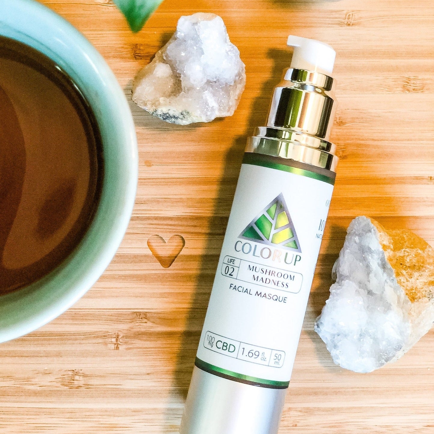 'Color Up Mushroom Madness' Facial mask bottle on a wooden surface with a cup and crystals.