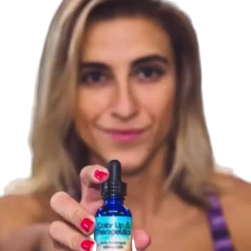 Woman holding a blue bottle with a dropper labeled 'Color Lip & Cheek' against a dark background
