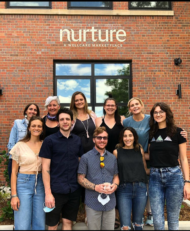 Group of people posing in front of a building with 'Nurture' branding.