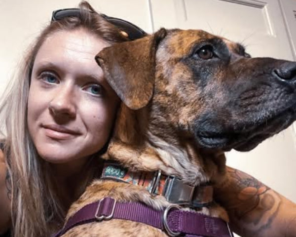 Female Color Up employee with Color Up pup a brown dog with black markings