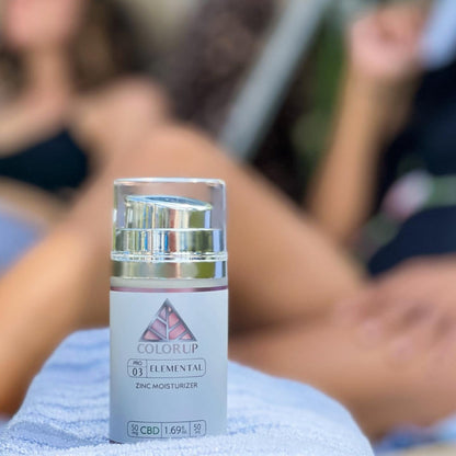 Skincare bottle labeled 'ColorUp' on a blurred background of people lounging.