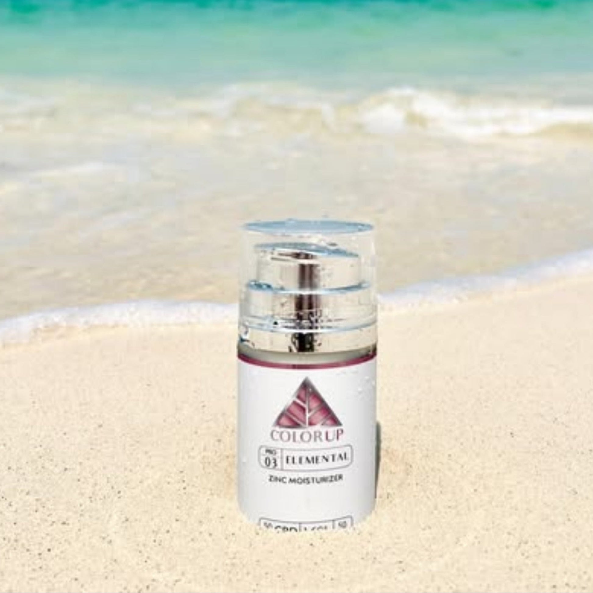 Skincare bottle labeled 'ColorUP' on a sandy beach with ocean in the background