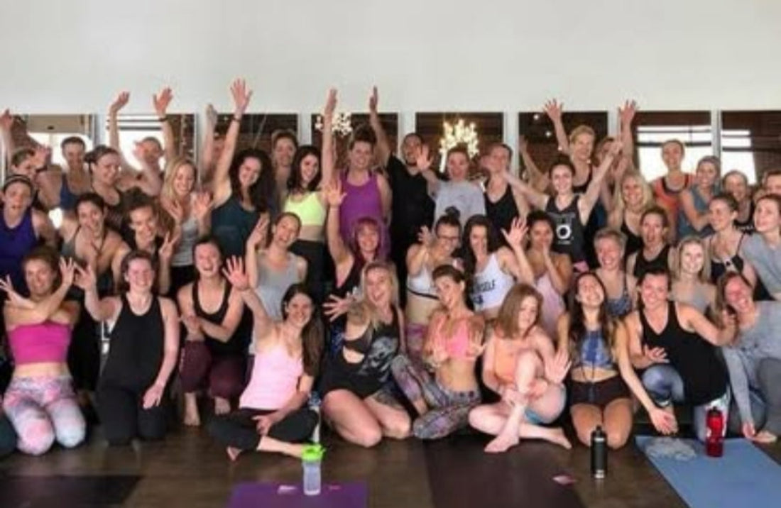 Group of people at Color Up Wellness Center posing together in a yoga studio with yoga mats on the floor.