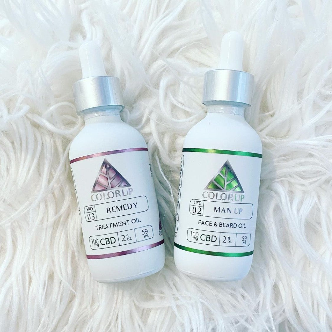 Two bottles of Color Up CBD products on a white textured background