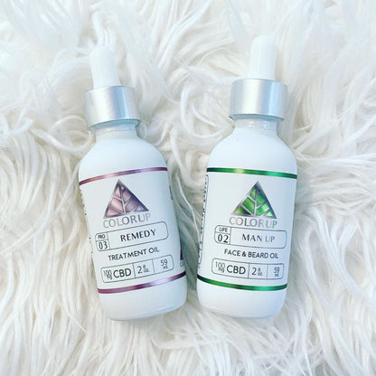 Two bottles of Color Up CBD products on a white textured background