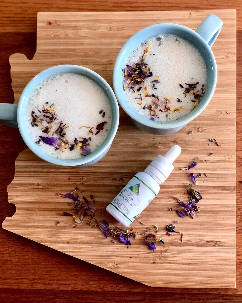 Two mugs of hot beverage with dried herbs on a wooden cutting board, accompanied by a bottle of Color Up Pure Sublingual.