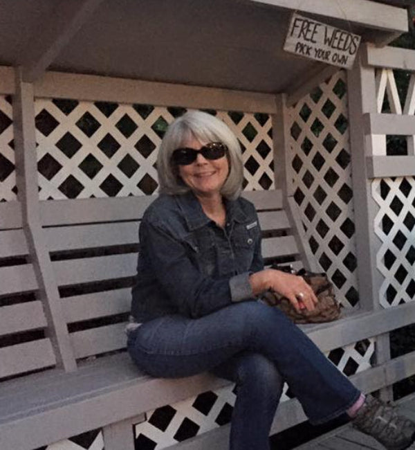 A woman sitting on a wooden deck with a white lattice fence.