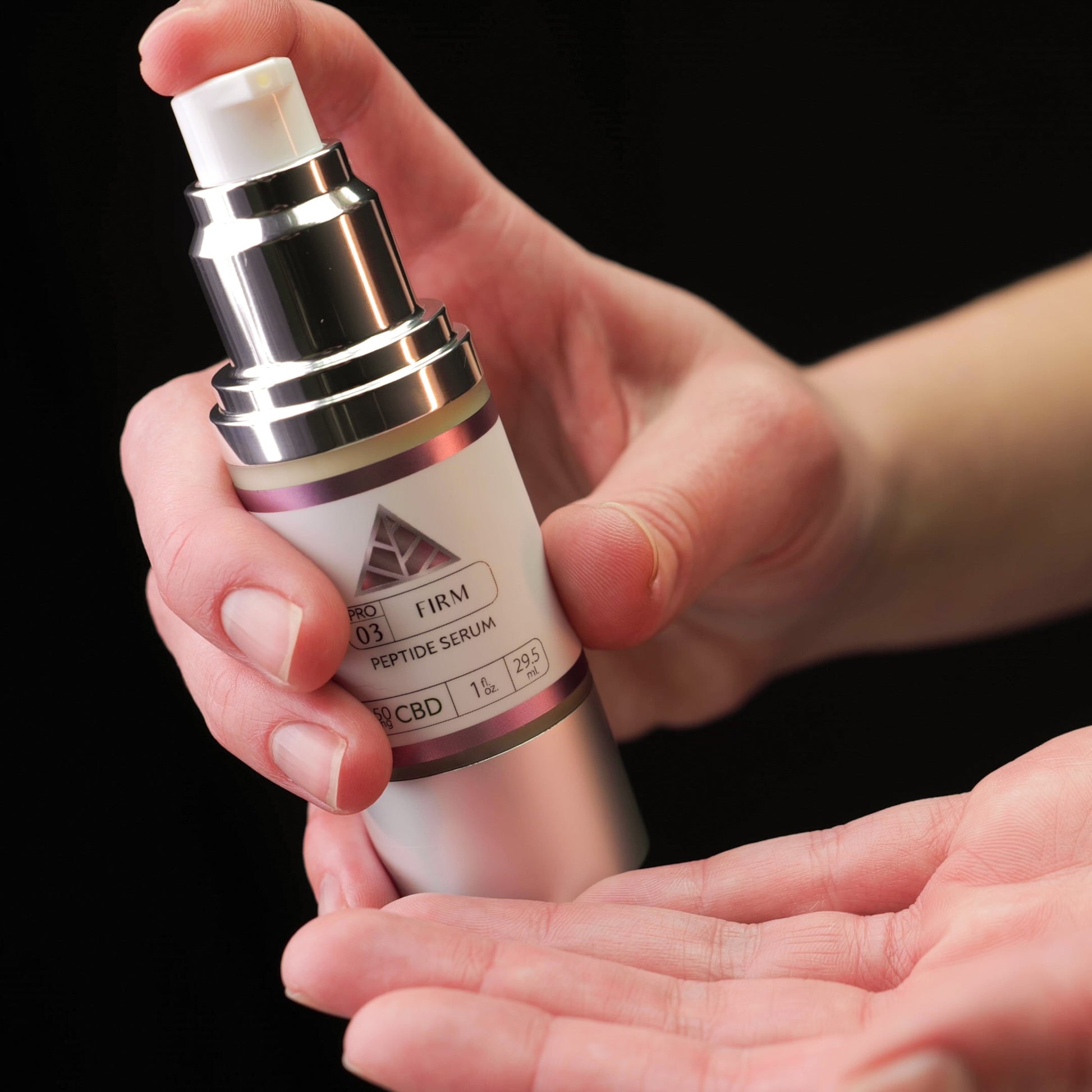Person holding a Color Up Firm Peptide Serum skincare product with a pink triangle logo