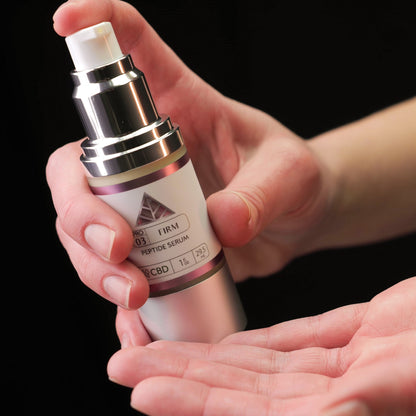 Person holding a Color Up Firm Peptide Serum skincare product with a pink triangle logo