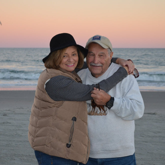 Two people embracing on a beach with a sunset in the background