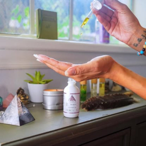 Person applying a dropper of liquid to their palm with a bottle labeled 'Alleviate' on a shelf.