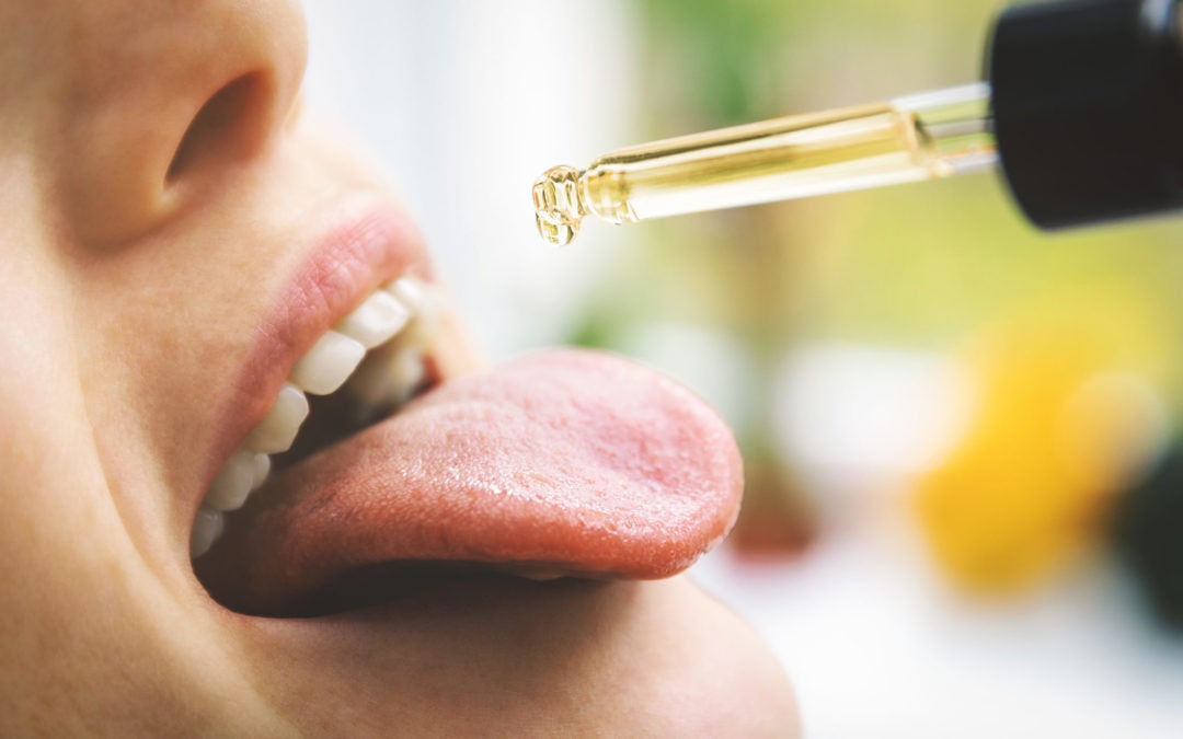 close up of woman putting a drop of CBD oil on her tongue using CBD for migraines